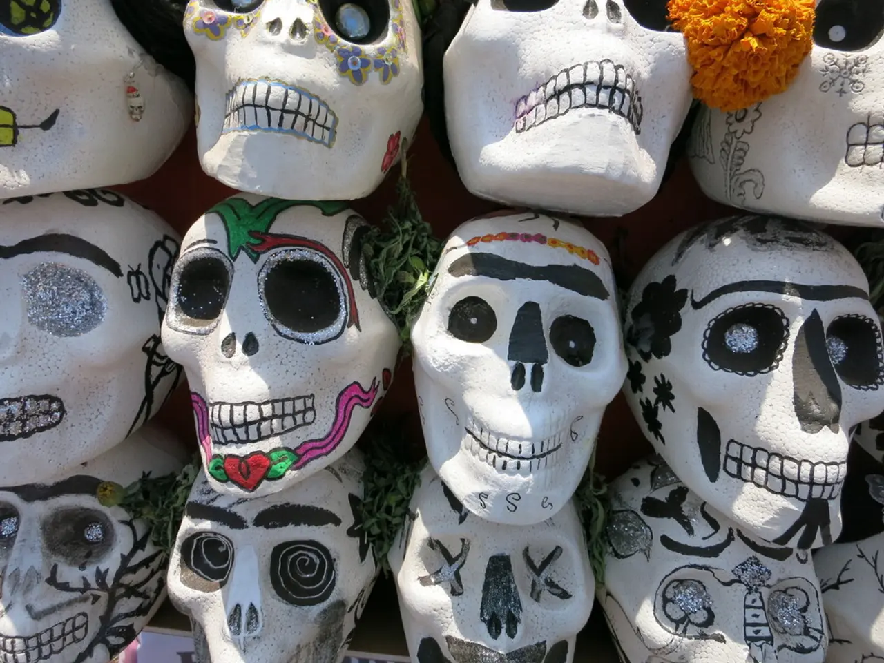 In this image we can see few objects with the shape of the skull and we can see a flower and leaves...