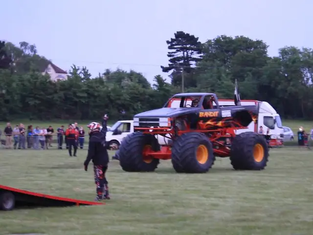 This looks like a monster truck. I can see a van and the cars, which are parked. There are groups...