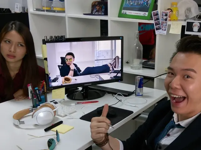 The person wearing black suit is sitting in a chair and holding a mobile phone and there is a table...