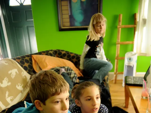 In this image two kids are lying on the sofa having cushions and a cloth. The kid at the left side...
