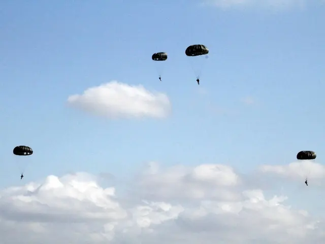 In this image I can see people are in the air along with parachutes. In the background of the image...