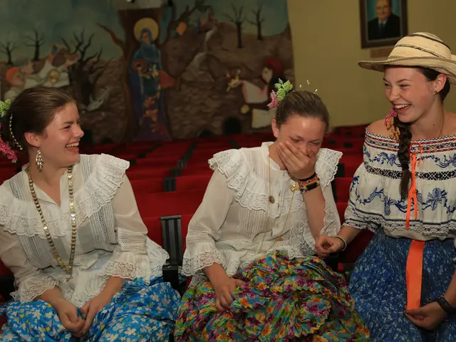In this image we can see three women are sitting and laughing. They are wearing white color top...